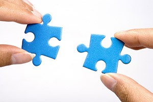 Asset Search - Two puzzle pieces held in fingers [Image © Shirley - Fotolia.com]